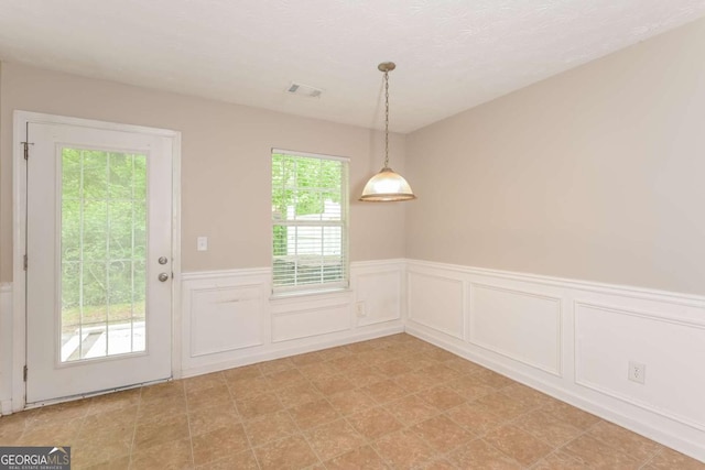 interior space with a wainscoted wall, a decorative wall, and visible vents