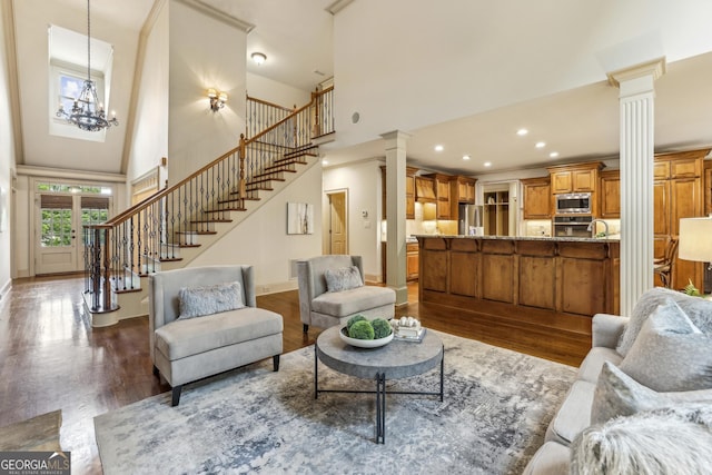 9075 Preston Ln, Suwanee, GA 30024 - living area featuring ornate columns, a towering ceiling, wood finished floors, stairs, and recessed lighting