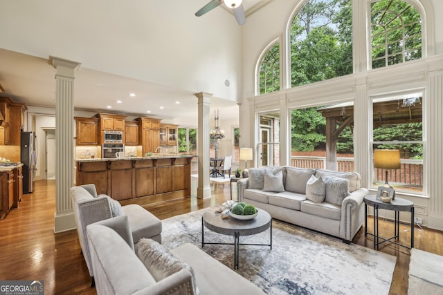 9075 Preston Ln, Suwanee, GA 30024 - living area featuring decorative columns, ceiling fan, wood finished floors, and a towering ceiling