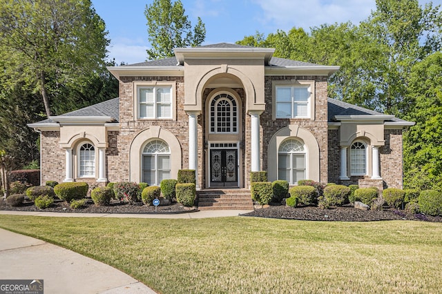 view of front of house with brick siding, a shingled roof, and a front yard