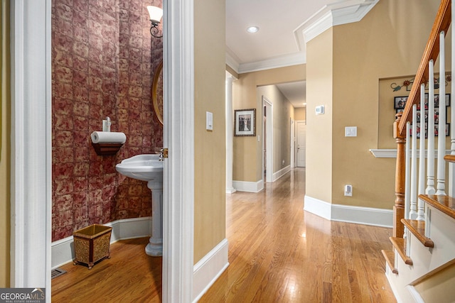 hall featuring crown molding, baseboards, wood finished floors, and stairway