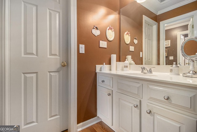 bathroom featuring vanity, ornamental molding, baseboards, and wood finished floors
