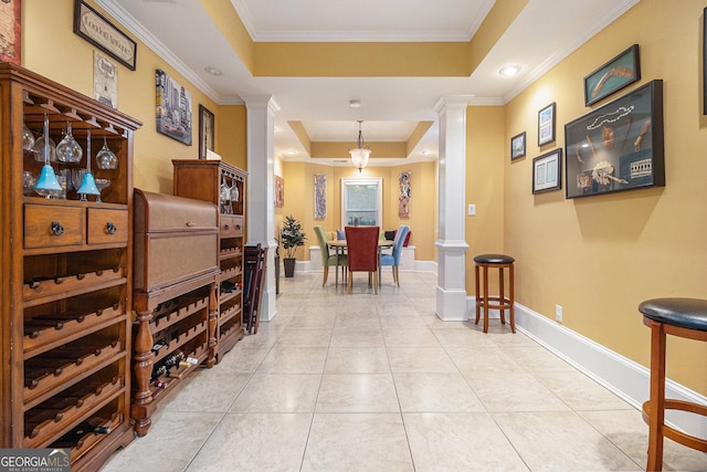 hall featuring crown molding, a raised ceiling, and decorative columns
