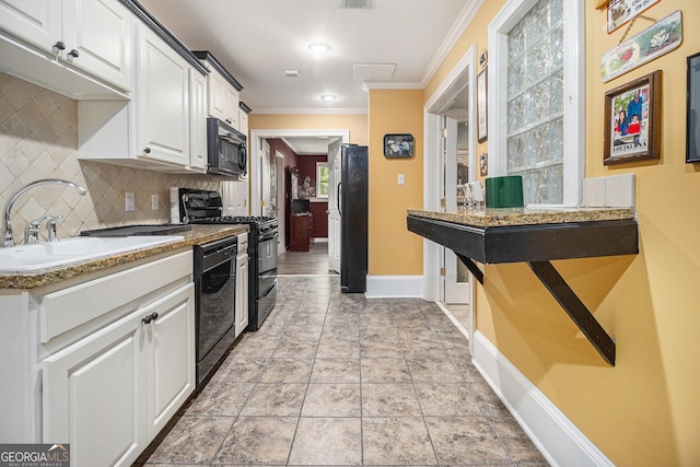 kitchen featuring crown molding, a sink, baseboards, decorative backsplash, and black appliances