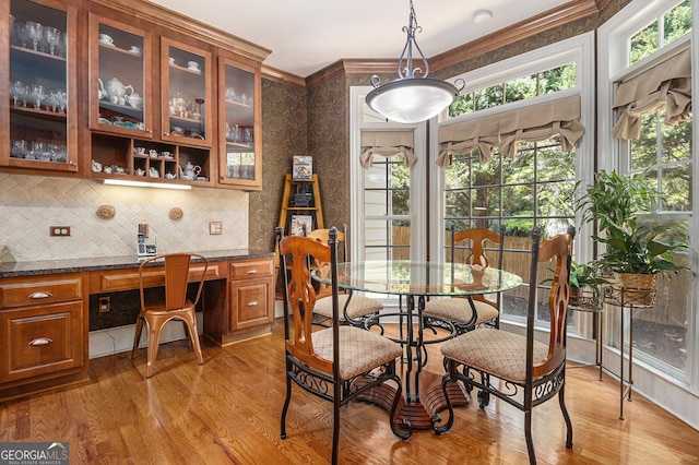 dining area featuring light wood-style floors, ornamental molding, and built in desk
