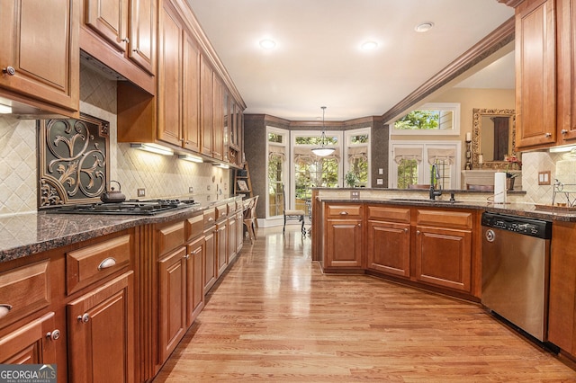 kitchen featuring brown cabinets, a sink, light wood-style floors, dishwasher, and backsplash