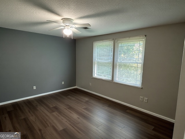 spare room featuring baseboards, ceiling fan, dark wood-type flooring, and visible vents