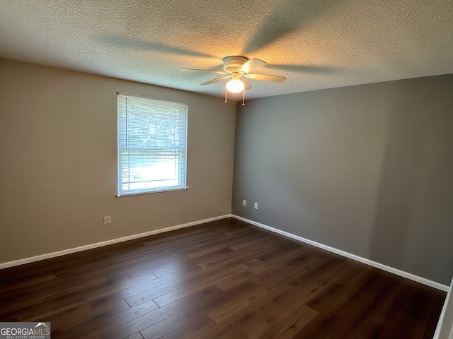 spare room featuring baseboards, ceiling fan, dark wood-style flooring, and a textured ceiling