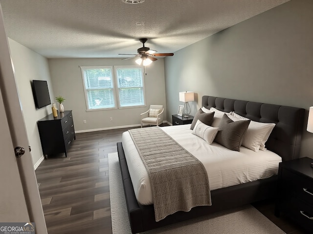 bedroom with baseboards, a ceiling fan, dark wood-style flooring, and a textured ceiling