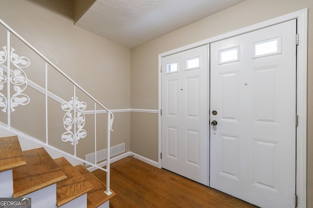entryway with visible vents, baseboards, wood finished floors, and stairway