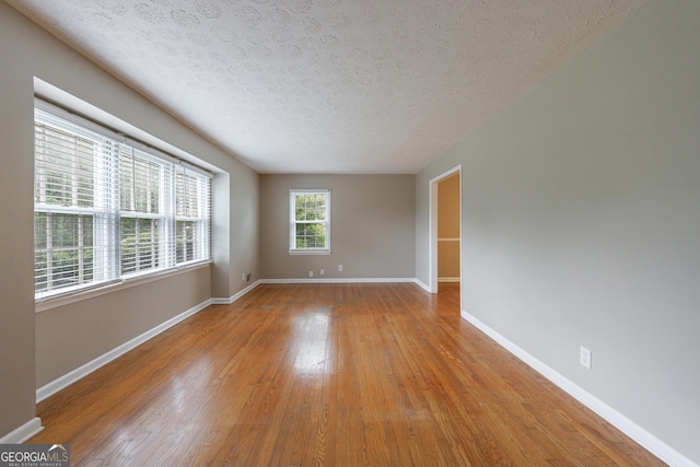 empty room featuring baseboards, a textured ceiling, and wood finished floors