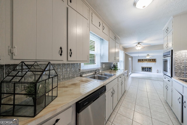 kitchen featuring ceiling fan, appliances with stainless steel finishes, a sink, light countertops, and decorative backsplash
