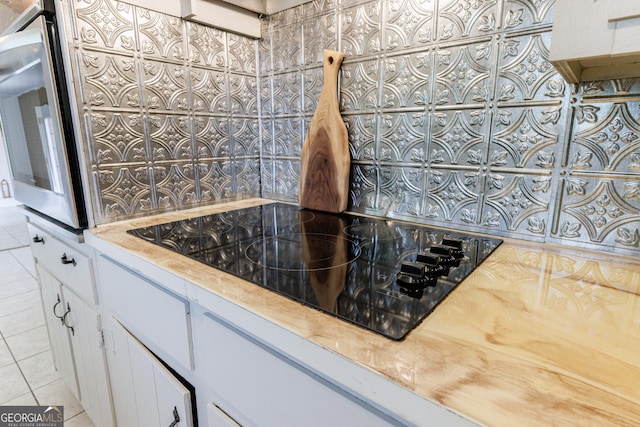 room details featuring light countertops, white cabinets, black electric stovetop, and oven