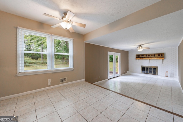 unfurnished living room featuring a ceiling fan, a textured ceiling, visible vents, light tile patterned floors, and baseboards