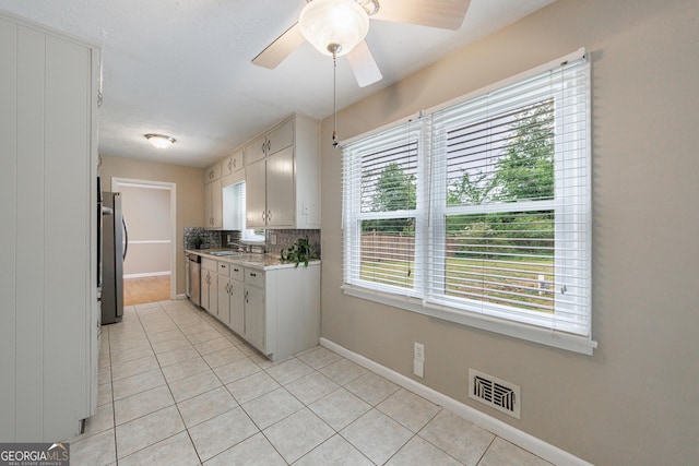 kitchen featuring baseboards, light countertops, a sink, light tile patterned floors, and stainless steel appliances