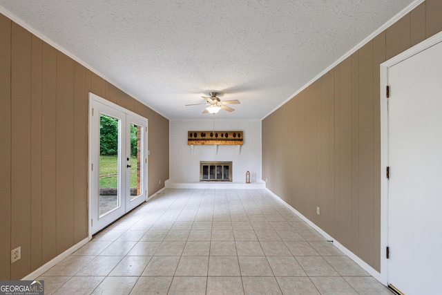 unfurnished living room with a brick fireplace, a textured ceiling, ceiling fan, and ornamental molding
