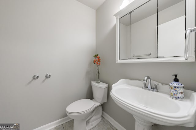 bathroom with a sink, baseboards, toilet, and tile patterned floors