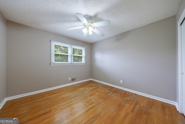 empty room featuring baseboards, a textured ceiling, light wood-style floors, and ceiling fan