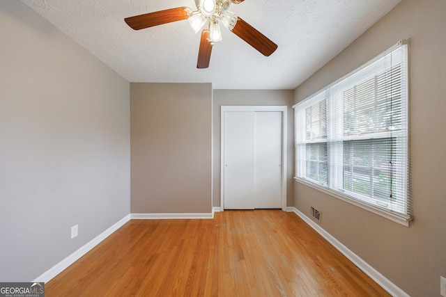 unfurnished bedroom featuring baseboards, a closet, light wood finished floors, and visible vents