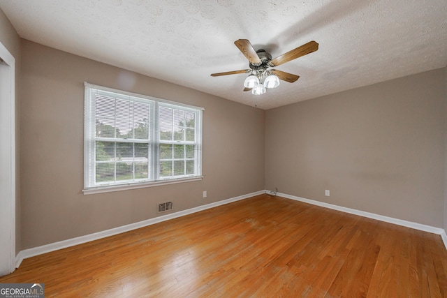 spare room featuring a ceiling fan, baseboards, visible vents, and light wood finished floors