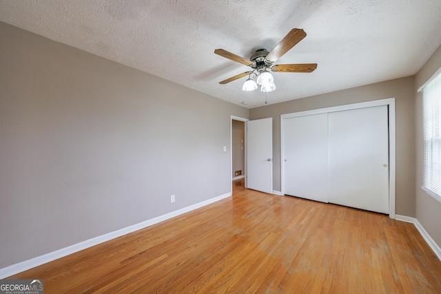 unfurnished bedroom featuring light wood finished floors, a textured ceiling, a ceiling fan, baseboards, and a closet