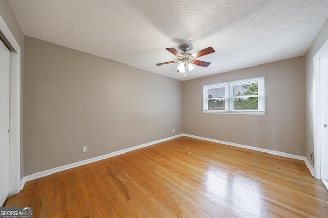 unfurnished bedroom featuring a textured ceiling, baseboards, a closet, and light wood-style floors