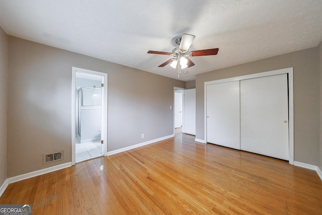 unfurnished bedroom with connected bathroom, light wood-style flooring, baseboards, visible vents, and a closet