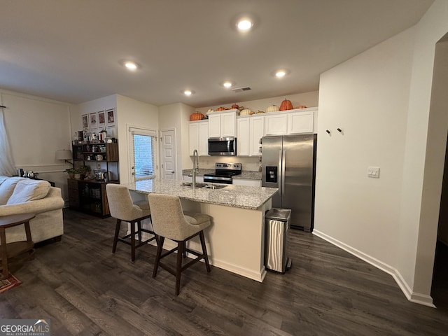 kitchen featuring a sink, appliances with stainless steel finishes, a kitchen island with sink, and dark wood finished floors