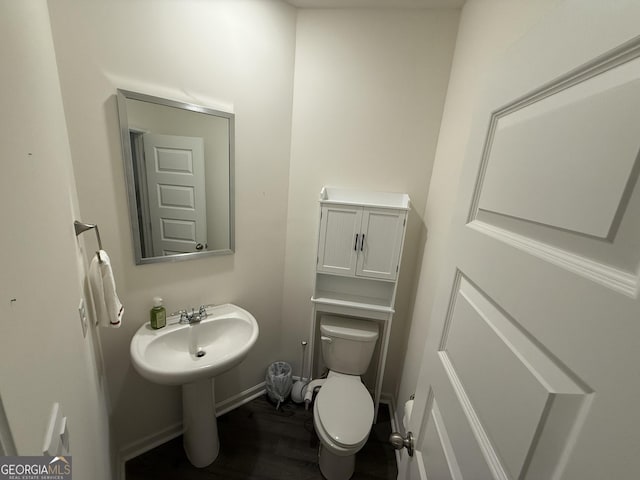 bathroom featuring baseboards, wood finished floors, and toilet