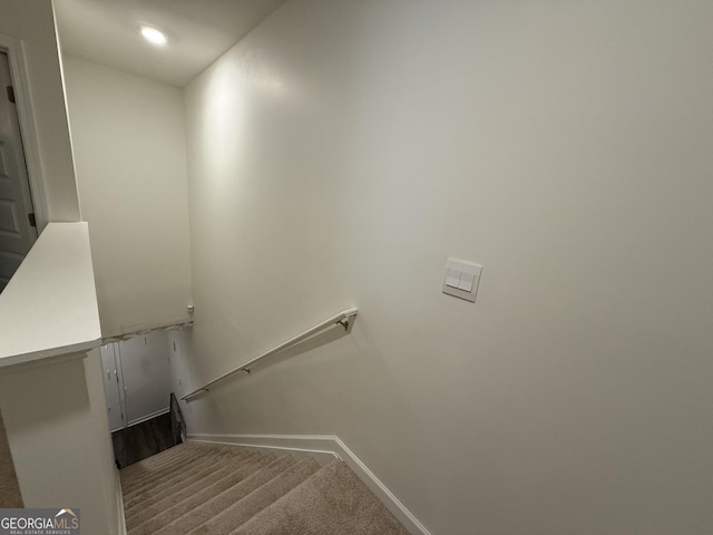 stairway featuring baseboards and carpet flooring