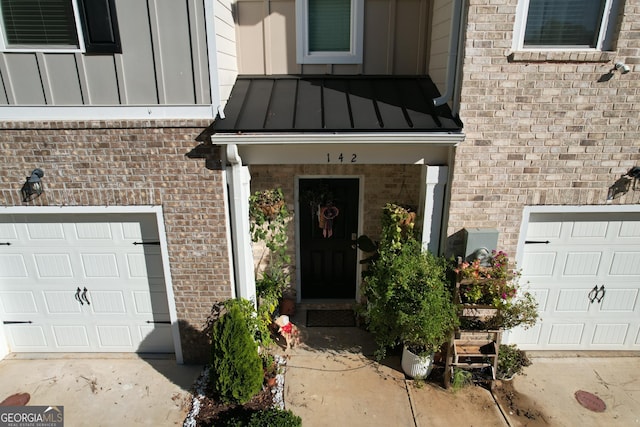 property entrance featuring a standing seam roof, an attached garage, and brick siding