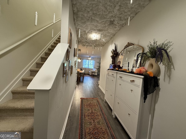 hall featuring baseboards, stairs, and dark wood-style floors