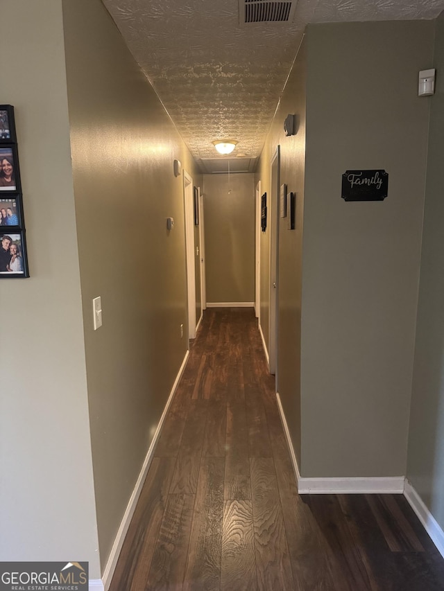 hallway featuring baseboards, attic access, wood finished floors, and visible vents