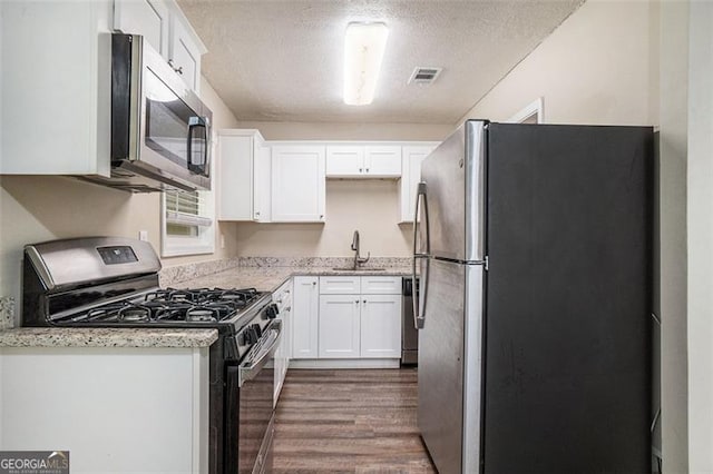 4004 Knightsbridge Rd, Kennesaw, GA 30144 - kitchen with a sink, stainless steel appliances, white cabinetry, and wood finished floors