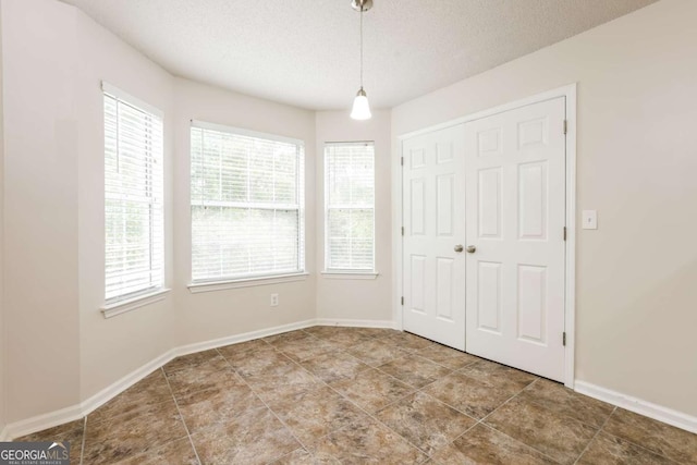 unfurnished bedroom with a textured ceiling, baseboards, tile patterned floors, and a closet