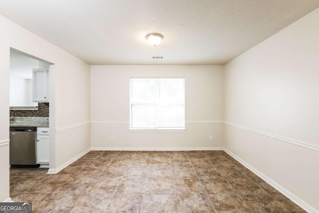 unfurnished dining area featuring a textured ceiling, visible vents, and baseboards