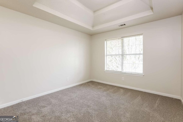 carpeted empty room with baseboards, a tray ceiling, and visible vents