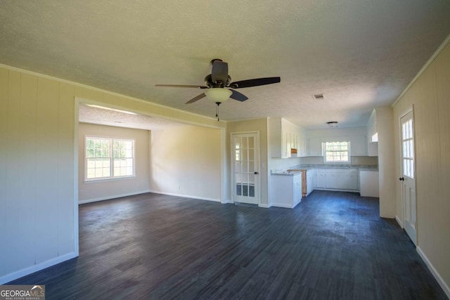 unfurnished living room featuring baseboards, a ceiling fan, a textured ceiling, and dark wood-style floors