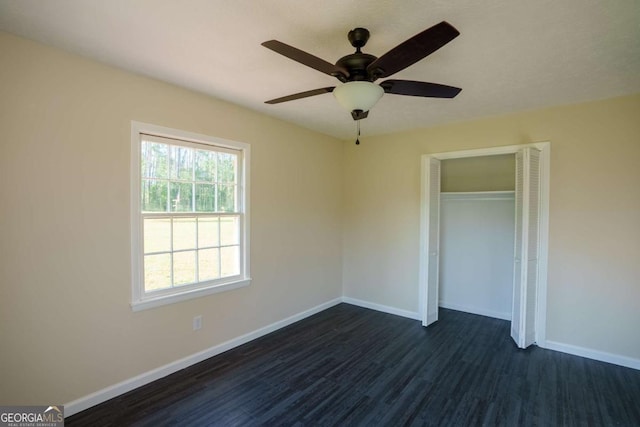 unfurnished bedroom featuring baseboards, ceiling fan, a closet, and dark wood-style floors