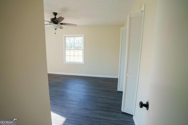 spare room featuring baseboards, a ceiling fan, and dark wood-style floors