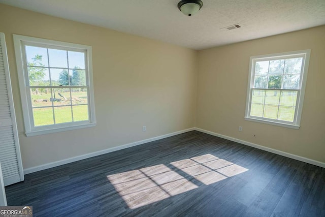 unfurnished room with dark wood-type flooring, baseboards, a healthy amount of sunlight, and visible vents