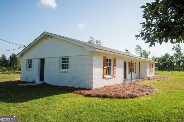 view of side of home featuring a yard and brick siding