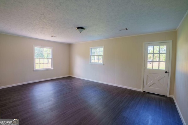 spare room with a textured ceiling, ornamental molding, baseboards, and dark wood-type flooring