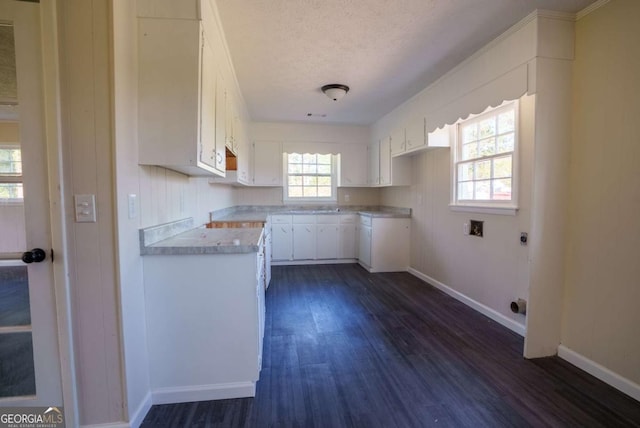 kitchen with a textured ceiling, dark wood finished floors, light countertops, baseboards, and white cabinets