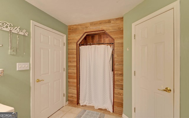 full bathroom featuring a shower with shower curtain, tile patterned floors, and wooden walls