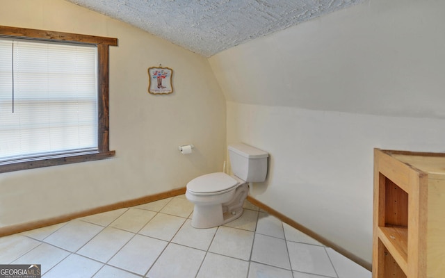 bathroom with baseboards, tile patterned flooring, vaulted ceiling, and toilet