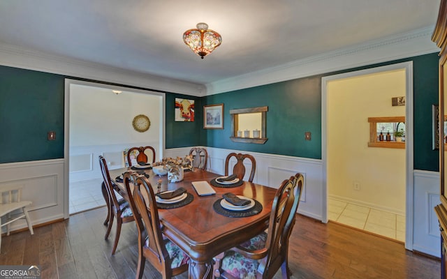 dining space with a wainscoted wall, ornamental molding, and wood finished floors