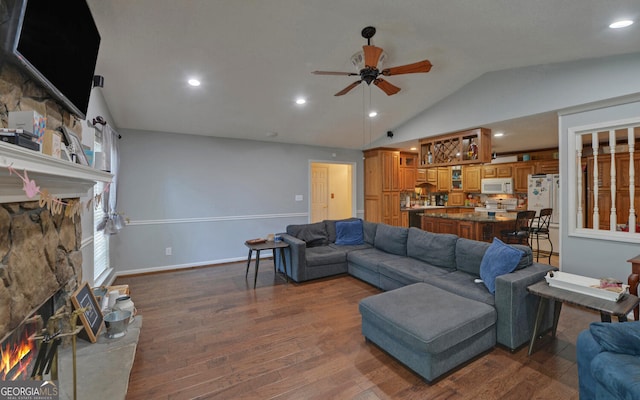 living room with a ceiling fan, dark wood finished floors, a stone fireplace, and lofted ceiling