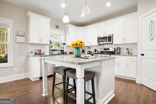 kitchen with dark wood-style flooring, a kitchen breakfast bar, tasteful backsplash, and stainless steel appliances
