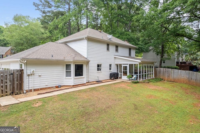 rear view of property with a sunroom, a shingled roof, a fenced backyard, and a yard